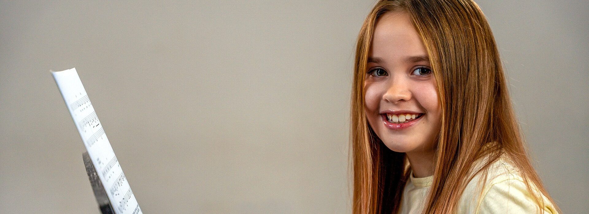 girl smiling while reading a music sheet