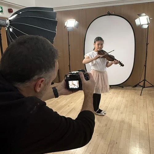 girl playing violin whilst being photographed