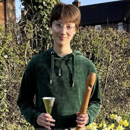 Young musician holding a flute and bell outdoors, representing Shropshire Music Service's focus on m.