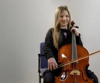 Young girl playing cello during a music performance at Shropshire Music Service.